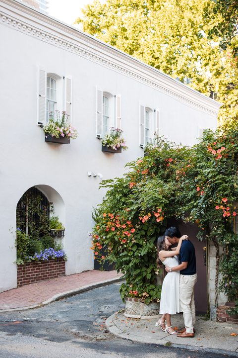 A kiss beside a white cottage draped in flowers